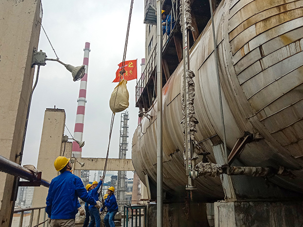 5月10日中午，在動(dòng)力車間三期工藝除氧器地面，黨員突擊隊(duì)隊(duì)員用滑輪往工藝除氧器平臺(tái)運(yùn)送鋼絲網(wǎng)，用以纏繞新填料.jpg