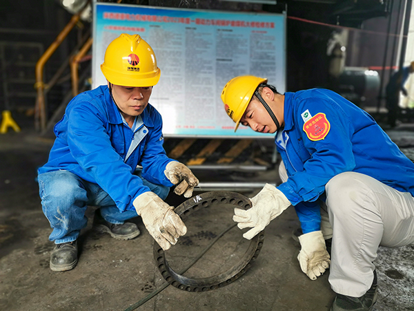圖三：12日下午14時(shí)，在一期磨煤機(jī)廠房，陜西省技術(shù)能手姬霄給青工張跟潮講解磨煤機(jī)搖臂曲拐內(nèi)環(huán)及動(dòng)作原理。.jpg